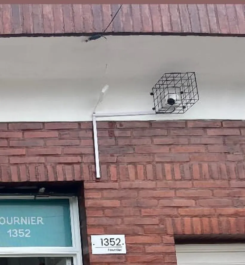 Cámara con jaula instalada sobre la pared de ladrillo de un local comercial, con la conexión en caja estanca